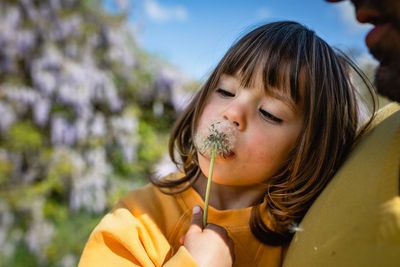 Portrait of small girl blowing dandelion