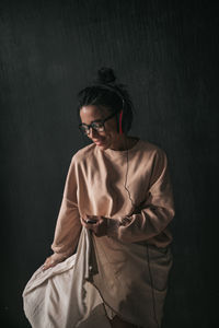 Woman looking away while standing against wall