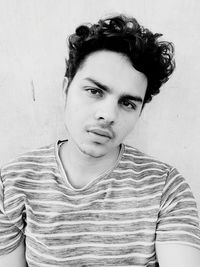 Portrait of young man standing against wall