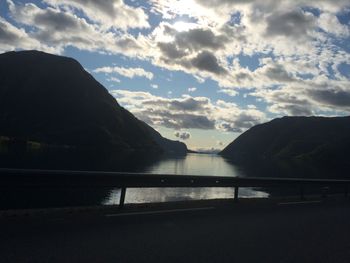 Scenic view of lake by silhouette mountains against sky