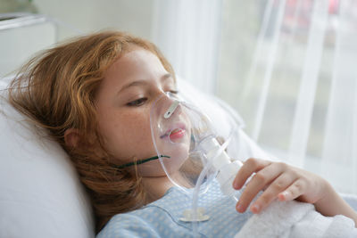 Girl with oxygen mask on bed at hospital