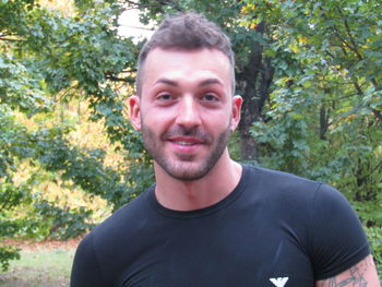 Portrait of smiling young man against trees