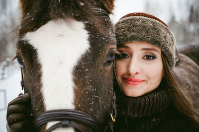 Close-up portrait of beautiful woman with horse during snowfall