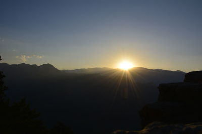 Sun shining through clouds over mountains