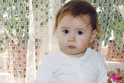 Portrait of cute baby girl against curtain