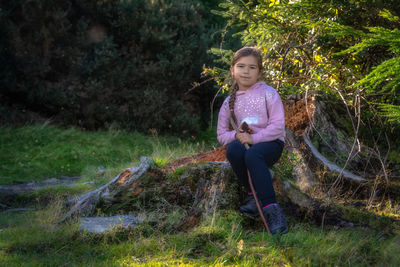 Girl sitting on a tree trunk in the forest, hiking in glendalough, wicklow mountains, ireland