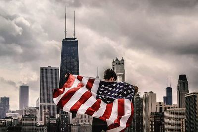 Man with flag standing against buildings in city