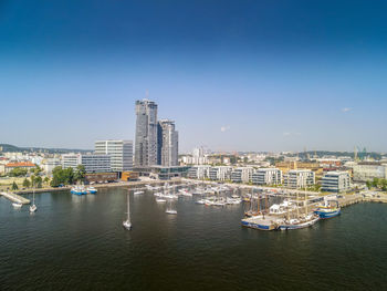 Sailboats in city by buildings against sky