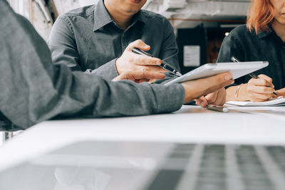 Midsection of man holding hands on table