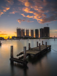 Damaged pier over sea against sky during sunset