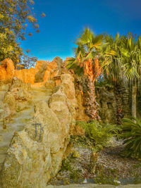 Rock formation and trees against blue sky