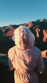 Rear view of man standing on mountain against sky