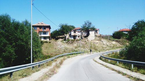 Road amidst trees and buildings against sky