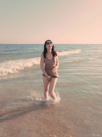 Full length of young woman standing on beach