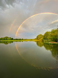 Scenic view of rainbow over lake against sky