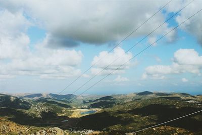 Power cables against mountains and sky