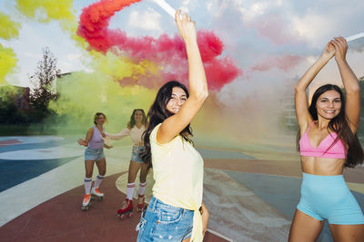 Happy friends enjoying together with smoke flare at sports court