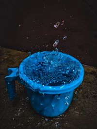 High angle view of blue water splashing on table