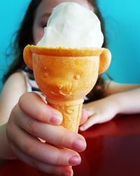 Close-up of girl holding ice cream on table at home