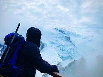 Man looking at snowcapped mountain against sky