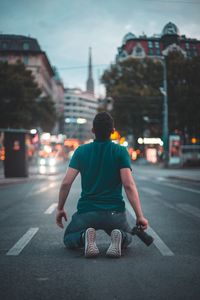 Rear view of man skateboarding on road in city