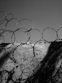 Low angle view of barbed wire fence against sky