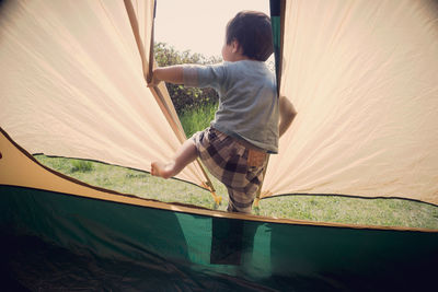 Rear view of boy playing in tent