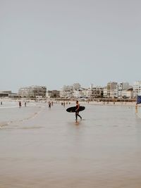 People on beach against clear sky