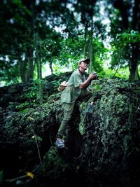 Woman standing by tree trunk in forest