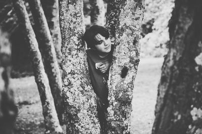 Portrait of young man standing on tree trunk