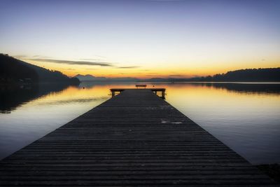 Pier over lake against sky during sunset