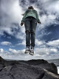 People standing on rock against cloudy sky