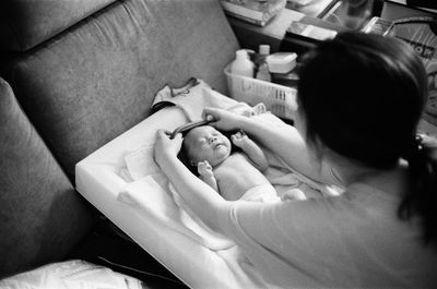 High angle view of mother getting baby dressed at home