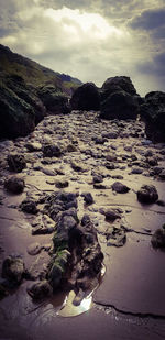 Rock formation on beach against sky