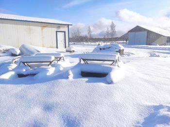 Snow covered field by buildings against sky