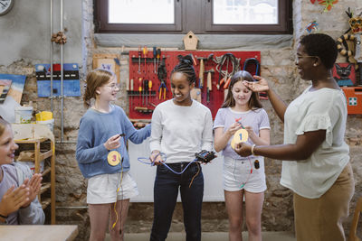 Teacher appraising female students at technology workshop in school