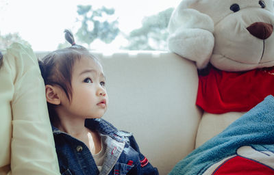 Close-up of cute baby girl sitting on sofa at home