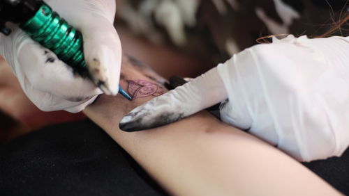 Cropped image of artist tattooing human hand