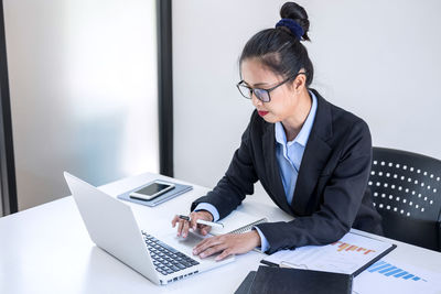 Businesswoman using laptop while sitting on table at office