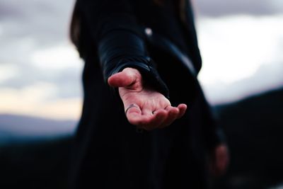 Close-up of hands against sky