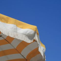 Low angle view of umbrella against clear blue sky