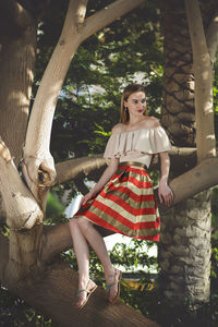 Young woman sitting on tree trunk