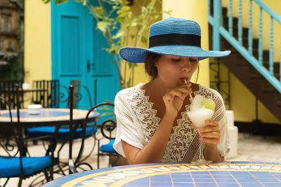 Portrait of woman wearing hat while sitting on table