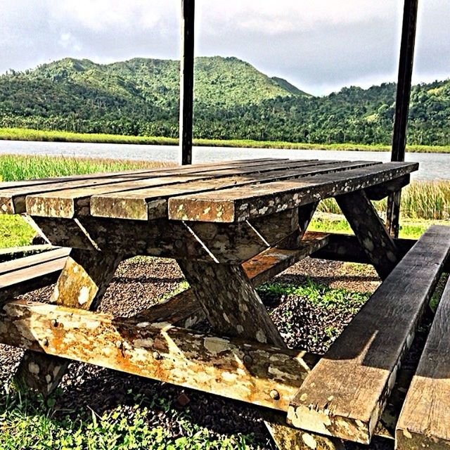 mountain, mountain range, landscape, tranquility, tranquil scene, grass, sky, scenics, nature, field, non-urban scene, wood - material, beauty in nature, bench, railing, day, empty, tree, outdoors, no people