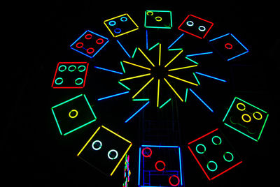 Low angle view of illuminated lighting equipment against black background