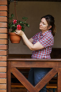 Woman holding flower pot on potted plant