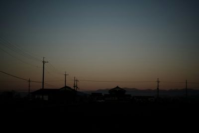 Silhouette of electricity pylon at sunset