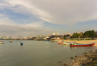 Boats moored on sea against cloudy sky during sunset