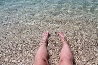 Low section of person legs on sand at beach