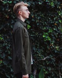 Side view of young man standing by plants